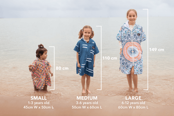 Kids hooded towel in geometric print patterns, shown in three sizes on beach models wearing navy, orange, and blue designs.