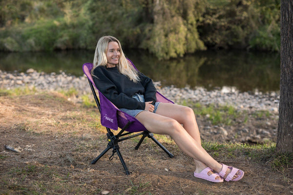 Woman relaxing in the Mulberry Purple camping chair by a river