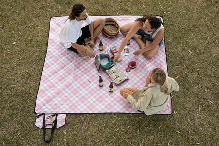 Image of three people sitting in Nakie's recycled picnic blanket, enjoying outdoor relaxation and sustainability.
