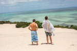 Image of two men wrapped in Nakie's recycled sand-free beach towel standing on a beach, admiring the view and enjoying sustainable comfort during their beach outing. preview #7