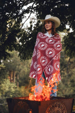 Burgundy and cream circular logo patterned beach towel draped over woman wearing cream cowboy hat by campfire preview #9
