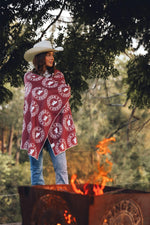 Burgundy printed beach towel with white circular logo pattern worn as a wrap over jeans and white cowboy hat preview #6