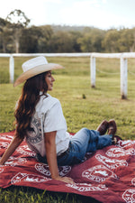 Ringers Western recycled picnic blanket in burgundy with cream logo pattern, displayed on grass field preview #5