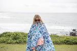 White, blue, and coral geometric patterned sustainable down puffy blanket draped around person at beach preview #10