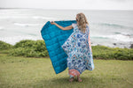 Bright turquoise quilted puffy blanket displayed outdoors with geometric patterned kimono at seaside. preview #8