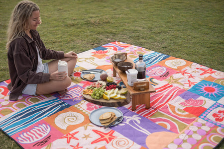 Colorful retro-print recycled picnic blanket with beach-themed motifs in pink, blue