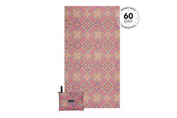 Recycled sand-free beach towel in coral, orange, and blue geometric diamond pattern with matching pouch.