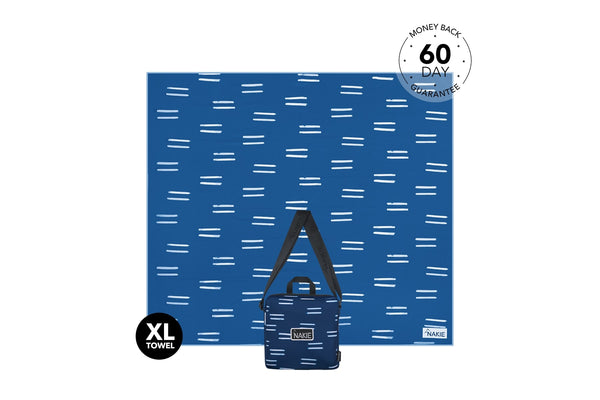 Blue XL recycled beach towel with white dash pattern, displayed with matching small bag, sand-free design